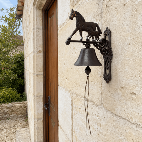 Wall-mounted horse and foal bell installed near an entrance