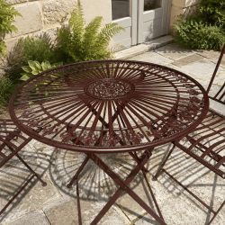 Round openwork metal garden table with floral medallion