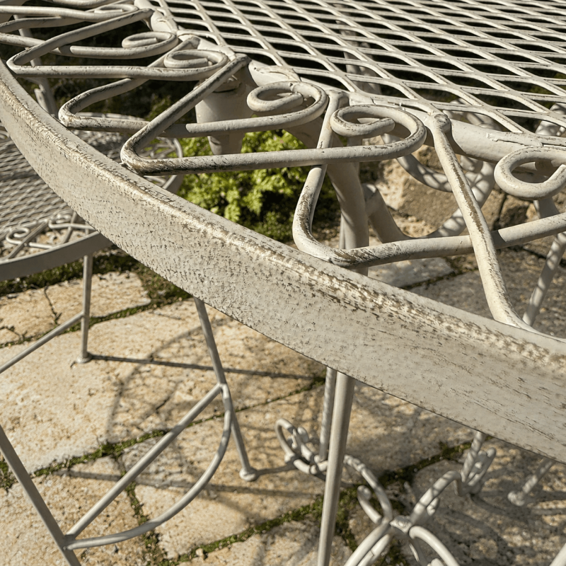 Decorative floral details on aged cream-white metal bistro set