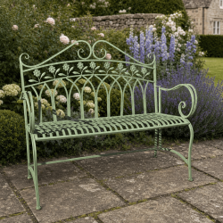 Patinated sage green metal garden bench in a romantic style