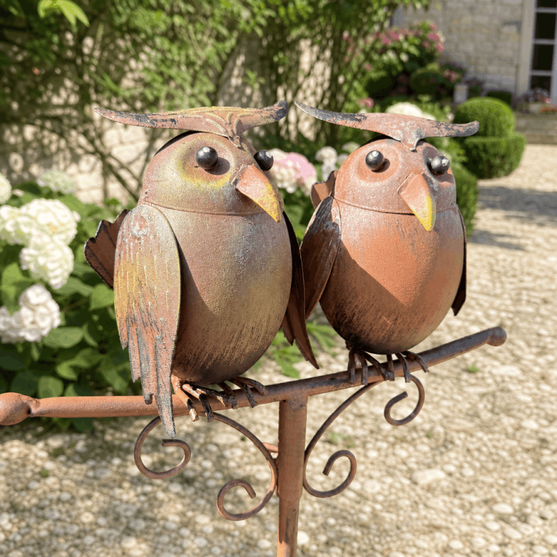 Two patinated metal owls on a decorative rain gauge
