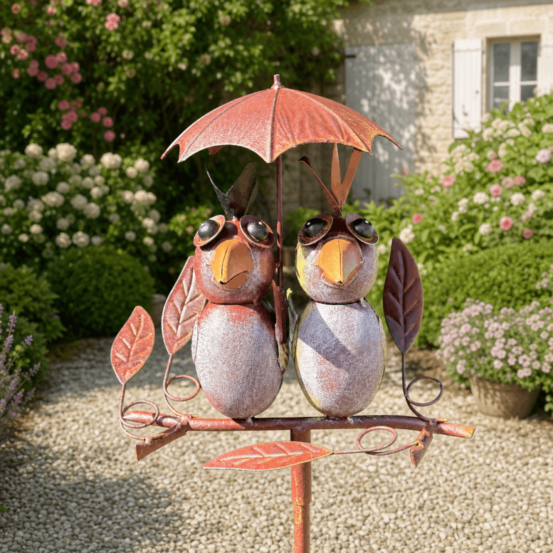 Two decorative metal birds under an umbrella for a garden rain gauge
