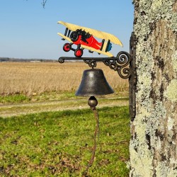 Cast iron wall bell mounted on a wall featuring a colorful biplane design