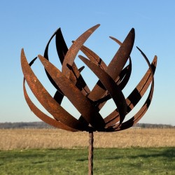 Full view of the sculptural decorative garden wind spinner in rusted metal under a clear sky
