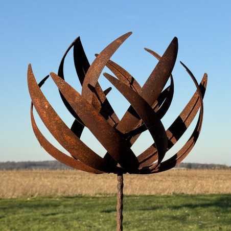 Full view of the sculptural decorative garden wind spinner in rusted metal under a clear sky