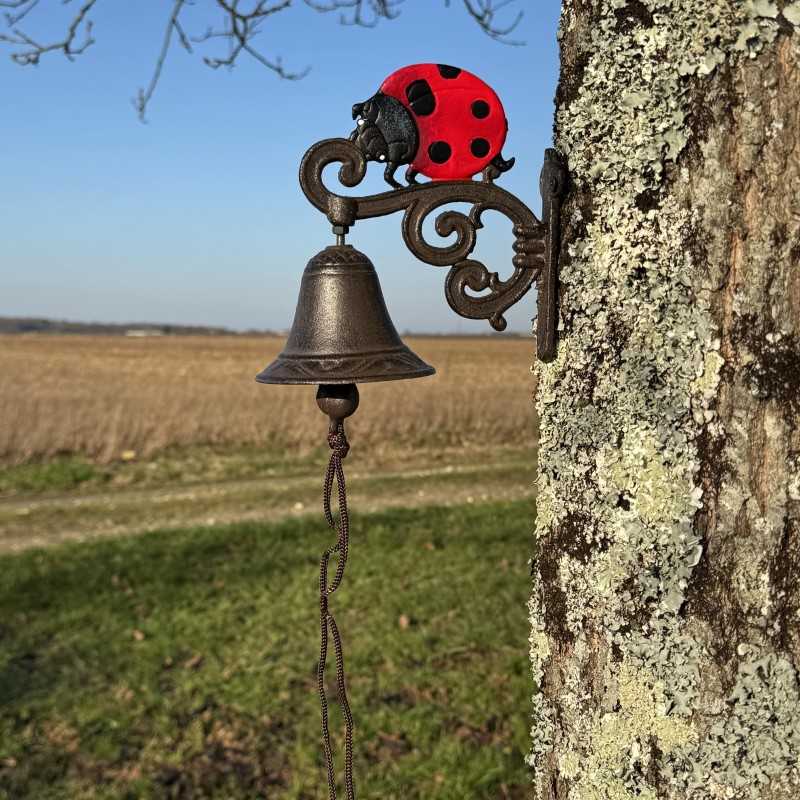 Cast-iron wall bell with a ladybug, set in a country setting