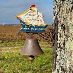 Wall-mounted cast iron doorbell with a sailboat, close-up view
