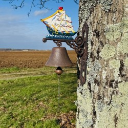 Wall-mounted cast iron doorbell with a sailboat design, staged with a small chain