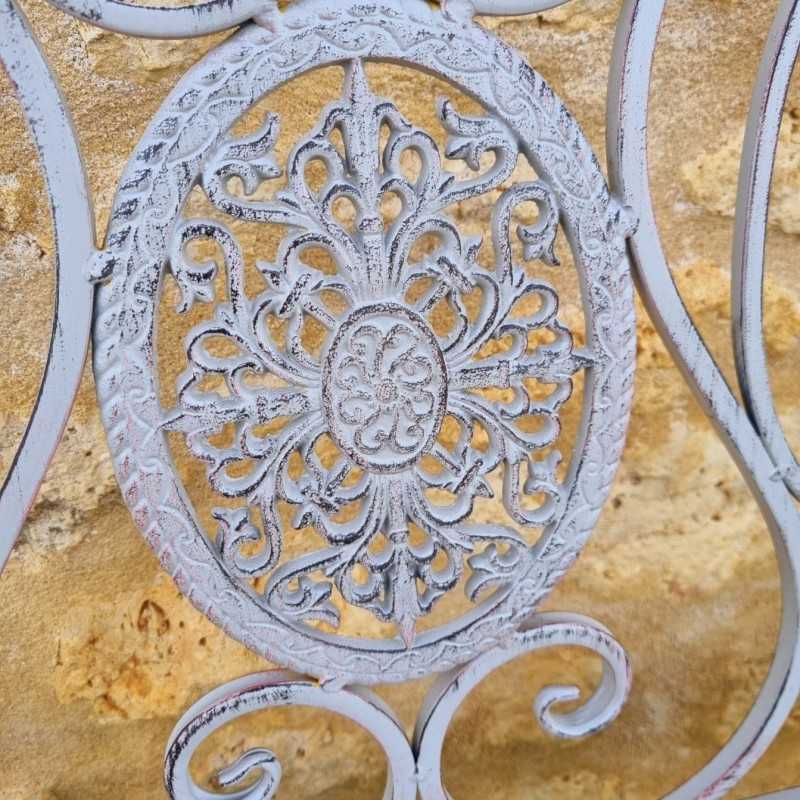Detail of the arabesques and cast-iron medallions on the weathered gray bench