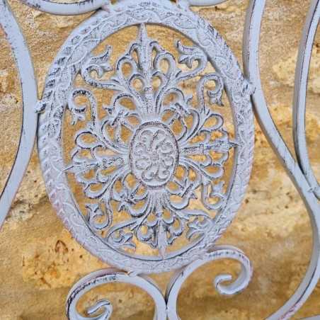 Detail of the arabesques and cast-iron medallions on the weathered gray bench