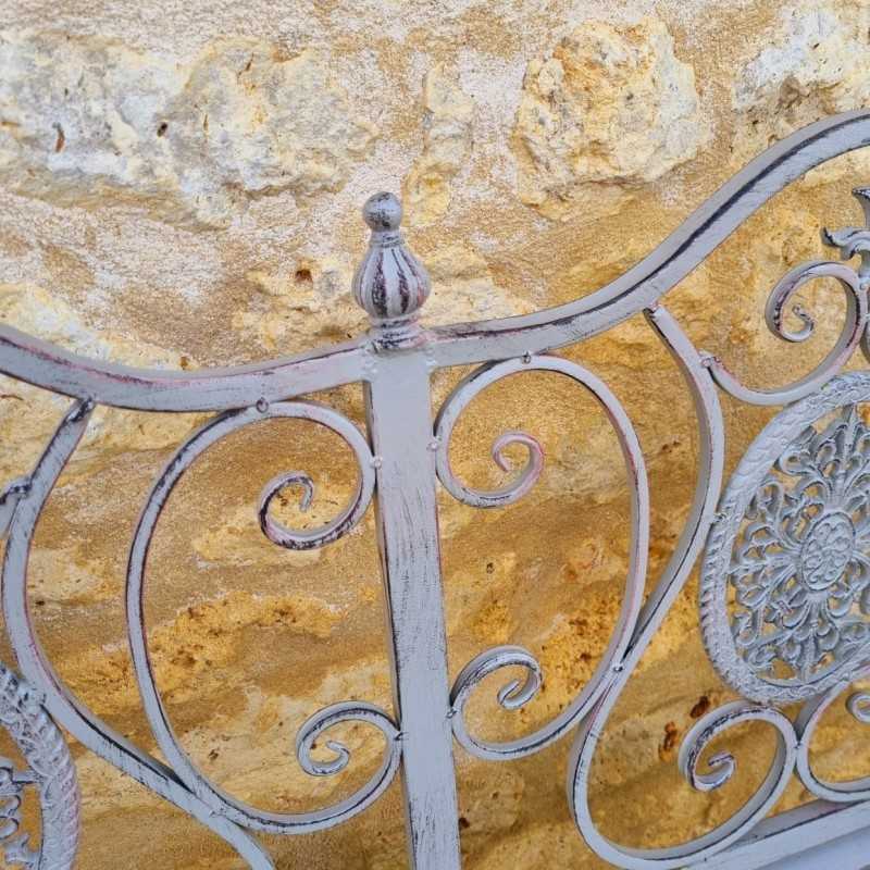 Two-seat wrought iron and cast-iron bench with a weathered finish, view of the finish