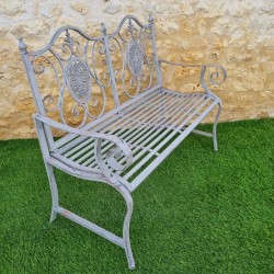 Two-seat wrought-iron and cast-iron bench with an aged gray patina on a terrace, side view