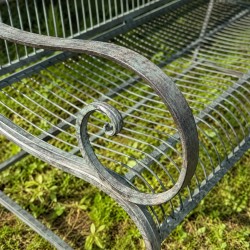 Detail of an old armrest on a weathered metal garden bench