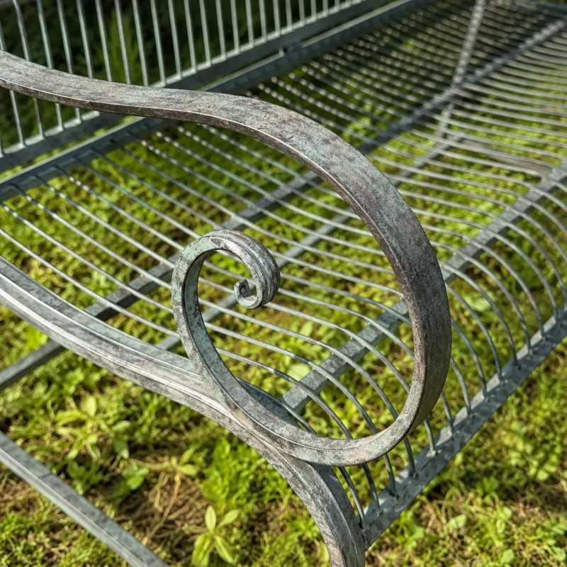 Detail of an old armrest on a weathered metal garden bench