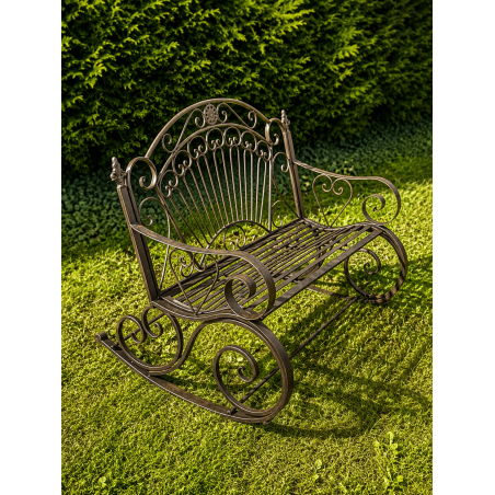 Patina-finished brown metal outdoor rocking bench – side view in a garden