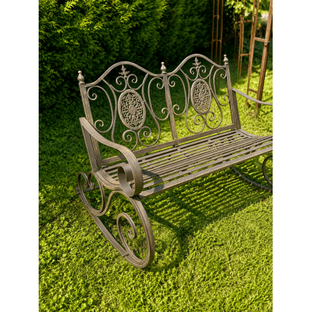 Weathered brown metal garden rocking chair, three-quarter view