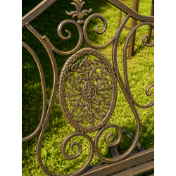 Patina-finished brown metal garden rocking chair, detailed view of the cast-iron medallion
