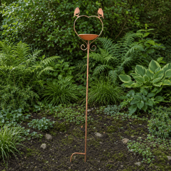 Heart-shaped bird feeder garden stake amongst plants