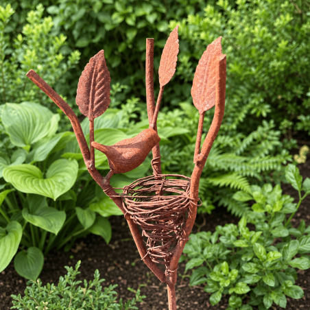 Metal bird beside woven nest with decorative leaves