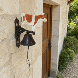 Large cast-iron cow doorbell mounted on a stone facade