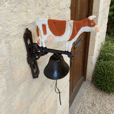 Cow-shaped wall doorbell installed near an entrance door